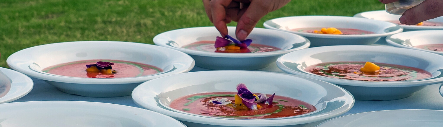 Garnishing gazpacho with edible flowers from the Arcturos Dining Series.