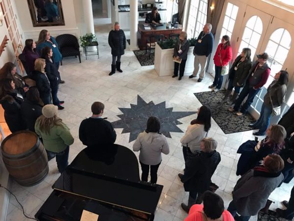 Tour group standing around the star on the floor of the foyer at the Inn at Black Star Farms, part of our Estate & Wine Tasting Tours.