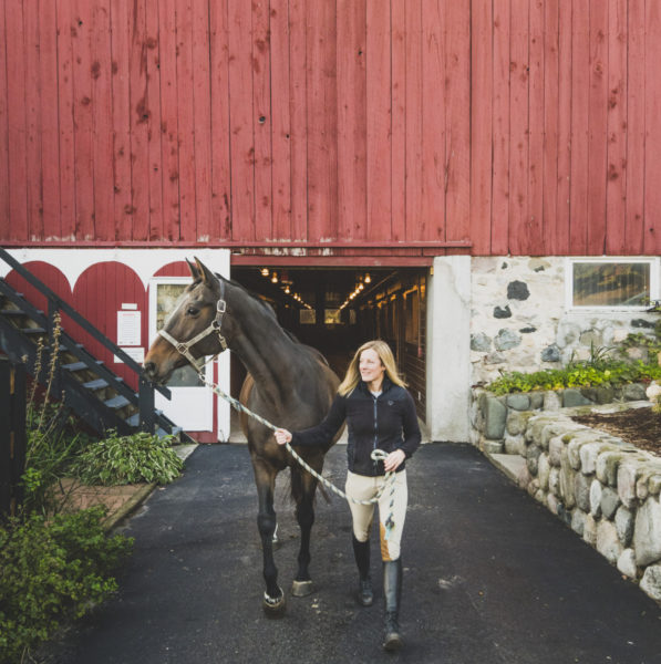 Women leading a horse from the barn at the Stables at Black Star Farms.