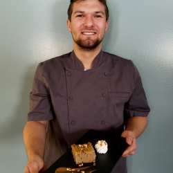 Employee and chef-in-training holding a piece of his Apple Upside-Down Spice Cake.