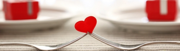Image of two forks balancing a red heart.
