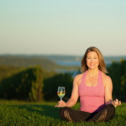 Yoga instructor in the vineyard with a glass of wine.