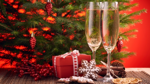 Two flutes of sparkling wine with Christmas cookies and festive background.
