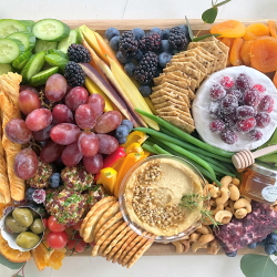 small charcuterie board with cheese, meat, crackers, fruit, and more.