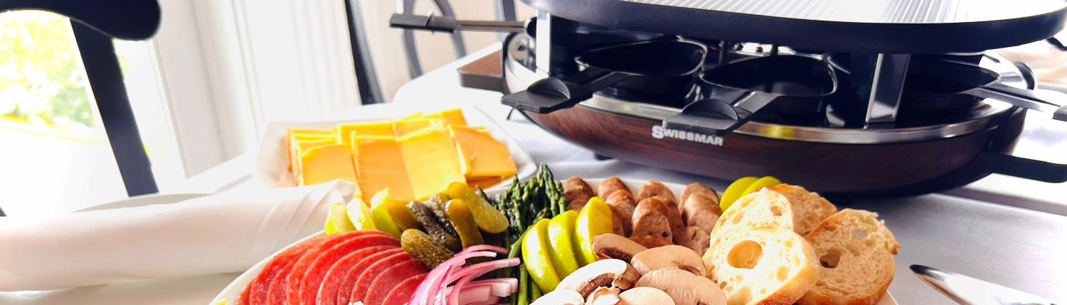 Raclette Grill with cheese, meats, vegetables, and bread.